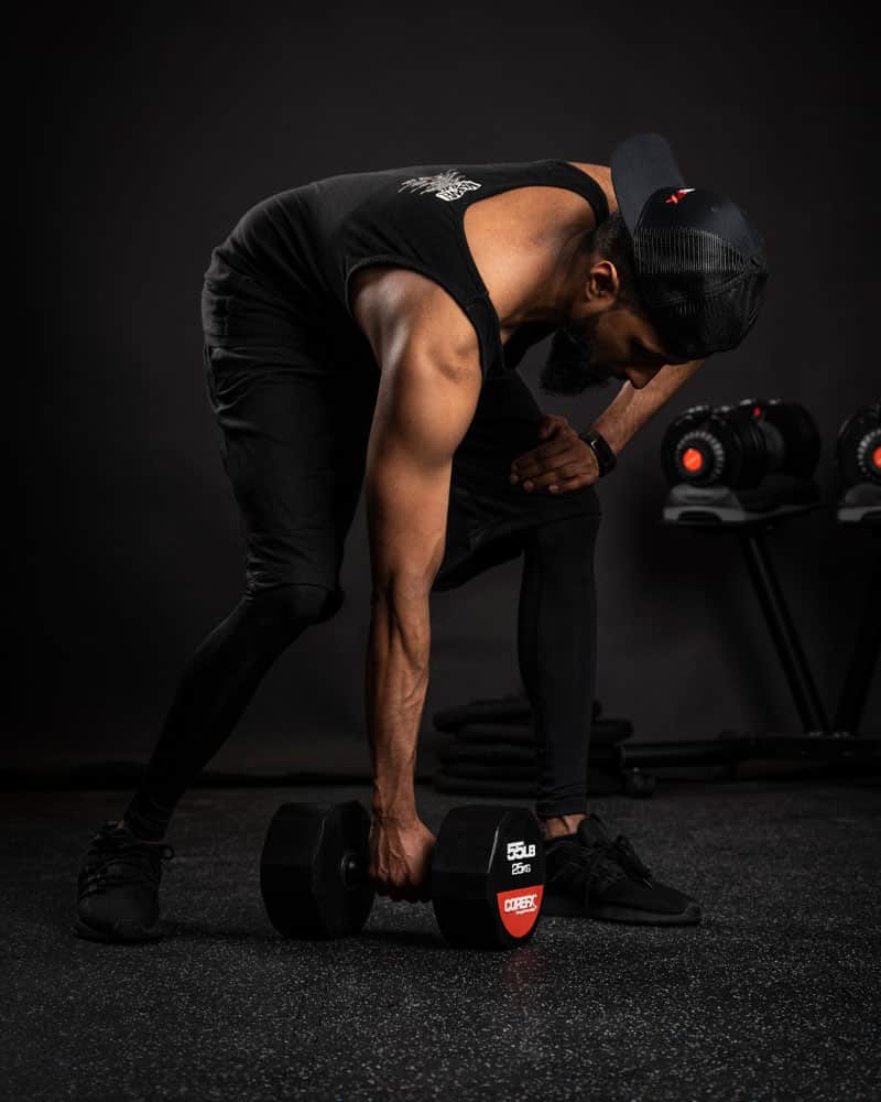 man picking up rubber dumbbell