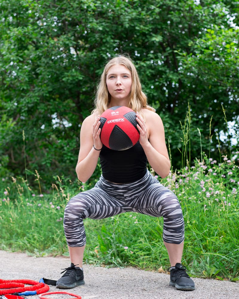 Woman doing squats with the COREFX Medicine Ball