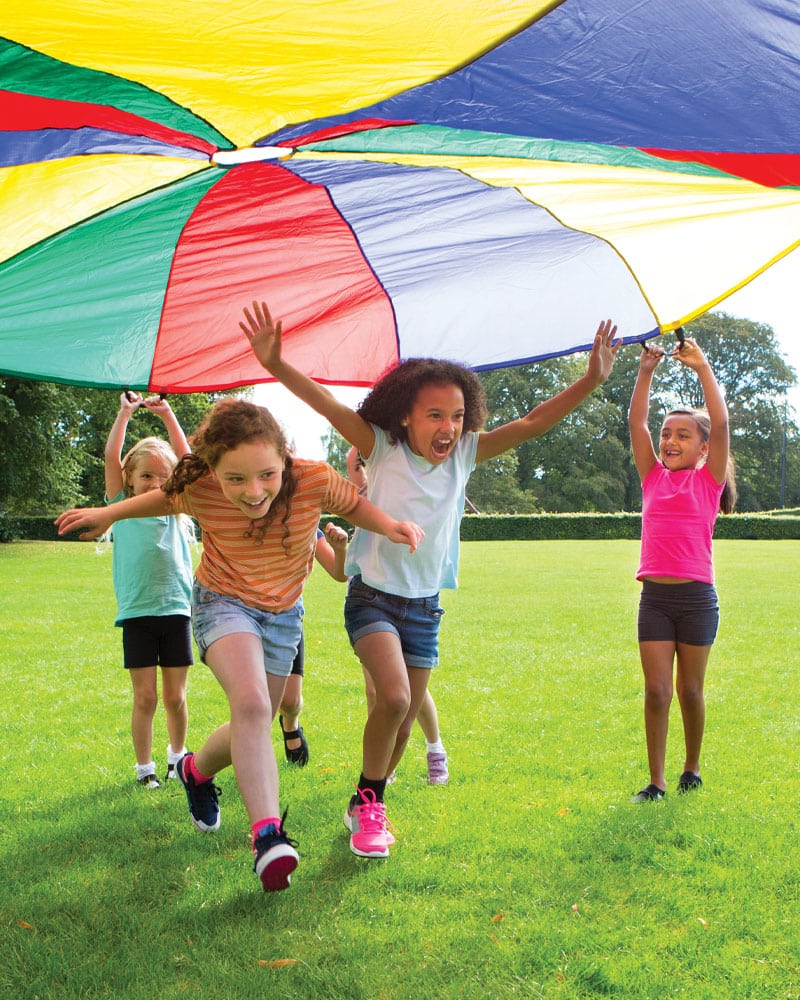 girls running under multi-coloured parachute
