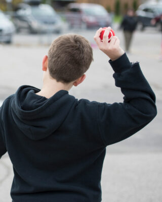 Boy throwing red practice tennis ball